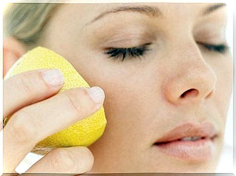 Woman smearing lemon on cheek - lemon as a natural cosmetic