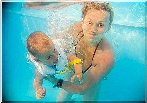 Woman in swimming pool with her baby