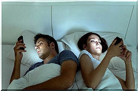 Couples lying in bed with each their phone