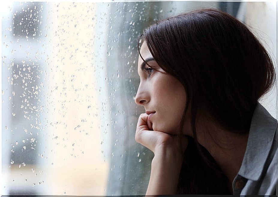 Woman staring out of a window with rain on