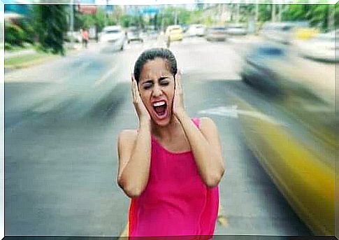 Woman on the road keeps her ears closed as noise affects her mood