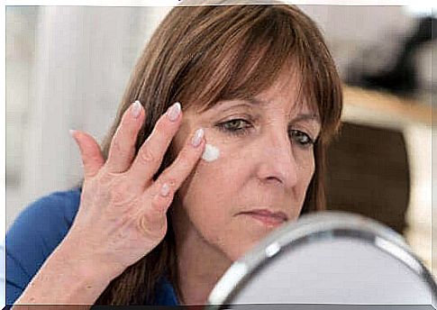 Woman smears a white cream on one cheek