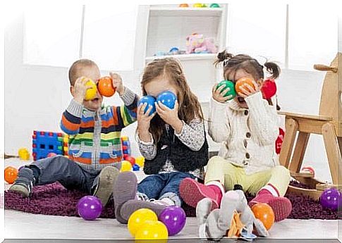 Three children play with colorful balls