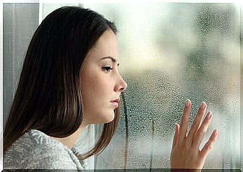 Woman by wet window suffering from holiday blues